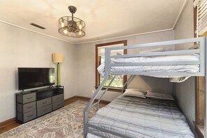A bedroom with bunk beds, a flat-screen TV, a dresser, and a patterned rug. - The Gainesville Rock House (Gainesville)