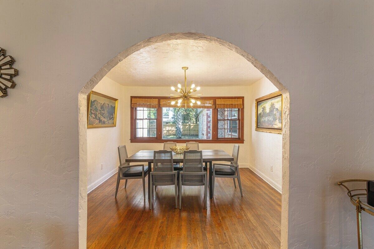 A dining area with a wooden table and chairs, a chandelier, and framed artwork on the walls.
