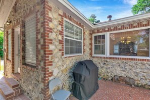 A stone and brick exterior with a covered grill, a window, and a chair. - The Gainesville Rock House (Gainesville)