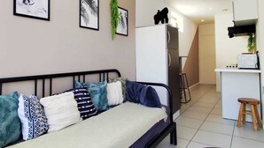 En kompakt bolig med seng, tekøkken og trappe op til en etage.