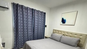 Ein Schlafzimmer mit einem Bett, Vorhängen, einer Wandlampe und einem gerahmten Bild.