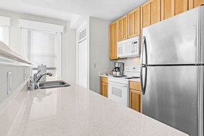 A modern kitchen with stainless steel appliances, wooden cabinets, and a granite countertop.