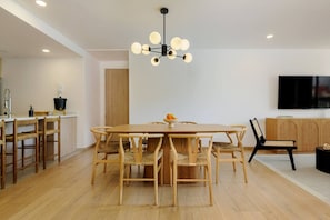 A modern dining area with a wooden table and chairs, a chandelier, and a television mounted on the wall. - Homey 3BR Apt near Parque México|Pool & Gym (Ciudad de México)