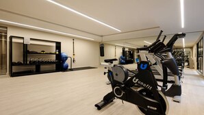 Ein Fitnessraum mit Trainingsgeräten, einer Spiegelwand und Holzboden.