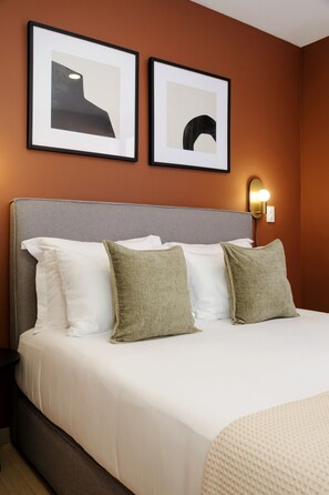 A hotel room with a bed, pillows, a nightstand, and two framed pictures on the wall. - Homey 3BR Apt near Parque México|Pool & Gym (Ciudad de México)