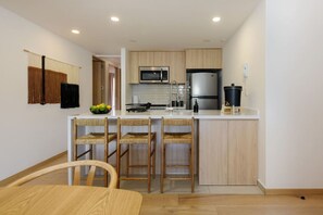A modern kitchen with a central island, wooden chairs, and a dining table. - Homey 3BR Apt near Parque México|Pool & Gym (Ciudad de México)