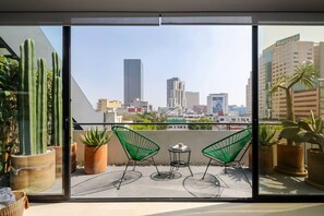 A balcony with two green wire chairs, potted plants, and a city skyline view. - ¡NEW! Modern apt. with Bellas Artes views (Ciudad de México)