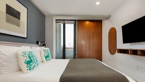 Ein Hotelzimmer mit einem Bett, einem Fernseher, einem Fenster und einer Tür.