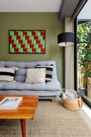 Ein modernes Wohnzimmer mit einem grauen Sofa, einer schwarzen Stehlampe und einem gewebten Korb.
