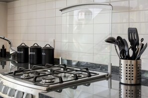A kitchen with a gas stove, three black containers labeled sugar, coffee, and tea, and a utensil holder with black utensils. - ¡NEW! Modern apt. with Bellas Artes views (Ciudad de México)