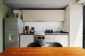 Cozinha compacta com geladeira, fogão e cafeteira.