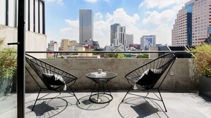 A rooftop terrace with two black wire-framed chairs and a small round table, overlooking a cityscape with various buildings. - Modern & Bright Apt. Steps from Revolución (Ciudad de México)