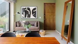 A modern living room with a sofa, coffee table, and a large abstract painting on the wall. - Modern & Bright Apt. Steps from Revolución (Ciudad de México)