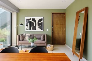 Uma sala de estar moderna com um sofá, mesa de centro e uma grande pintura abstrata na parede.