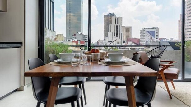 A modern dining area with a large table, black chairs, and a unique ceiling light fixture. - Modern & Bright Apt. Steps from Revolución (Ciudad de México)