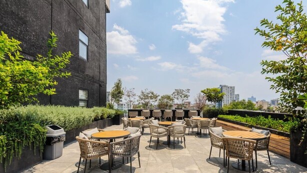 Un patio al aire libre con muebles de mimbre y vista a la ciudad.