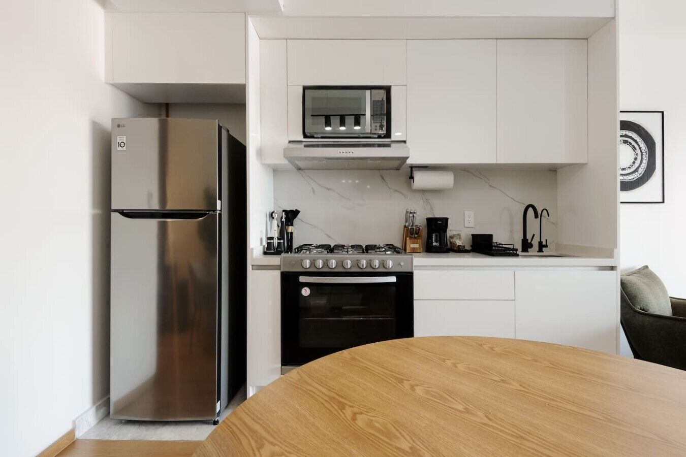 Une cuisine moderne équipée d’un réfrigérateur en acier inoxydable, d’une cuisinière et d’un four à micro-ondes.