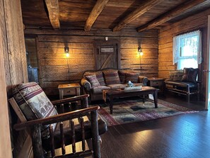 Ein rustikales Blockhaus-Interieur mit einer Couch, einem Sessel und einem kleinen Tisch.