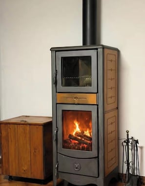 Un poêle à bois doté d’une porte en verre, d’un meuble en bois et d’un support en métal.