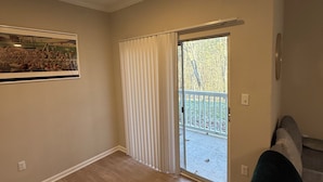 Ein Zimmer mit Holzboden, einer Schiebetür zum Balkon und einem gerahmten Bild an der Wand.