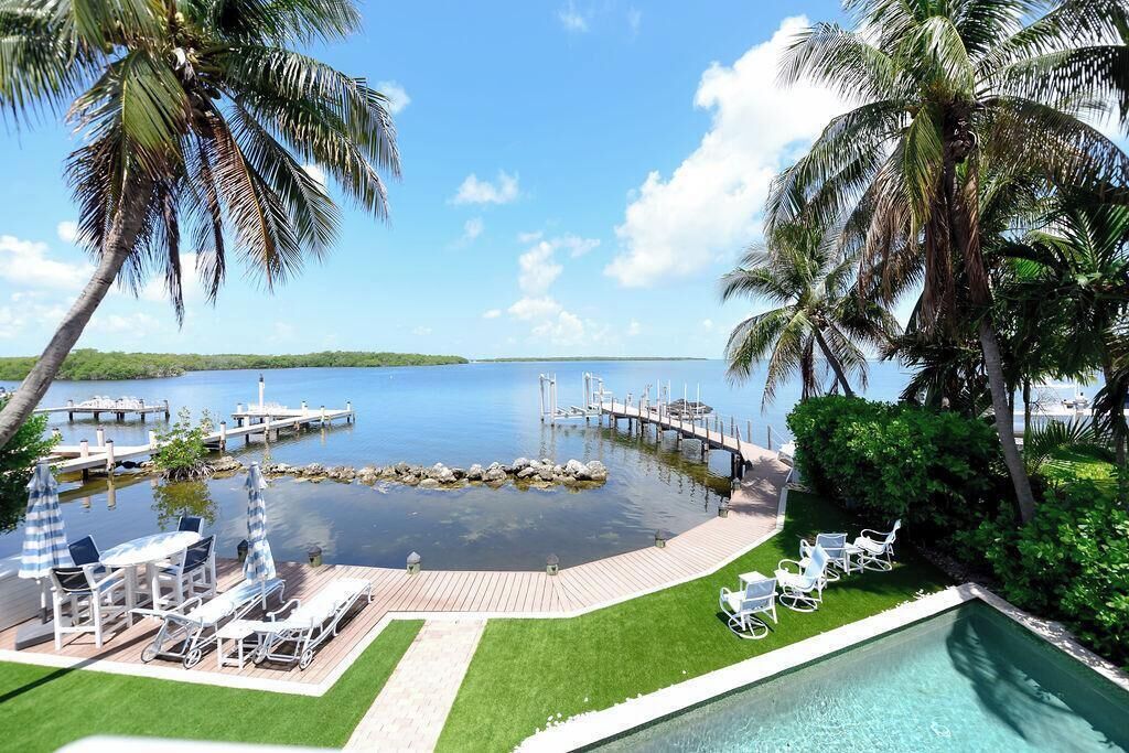 A pool area with lounge chairs, a dock, and a view of the water.
