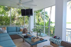 Ein geräumiger Balkon mit einer Couch, einem Tisch und einem Fernseher.