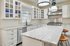 A modern kitchen with white cabinetry, a stainless steel stove, and a marble countertop. - Spacious 4-bedroom house in fabulous Southampton designed by former Vogue editor (Southampton)
