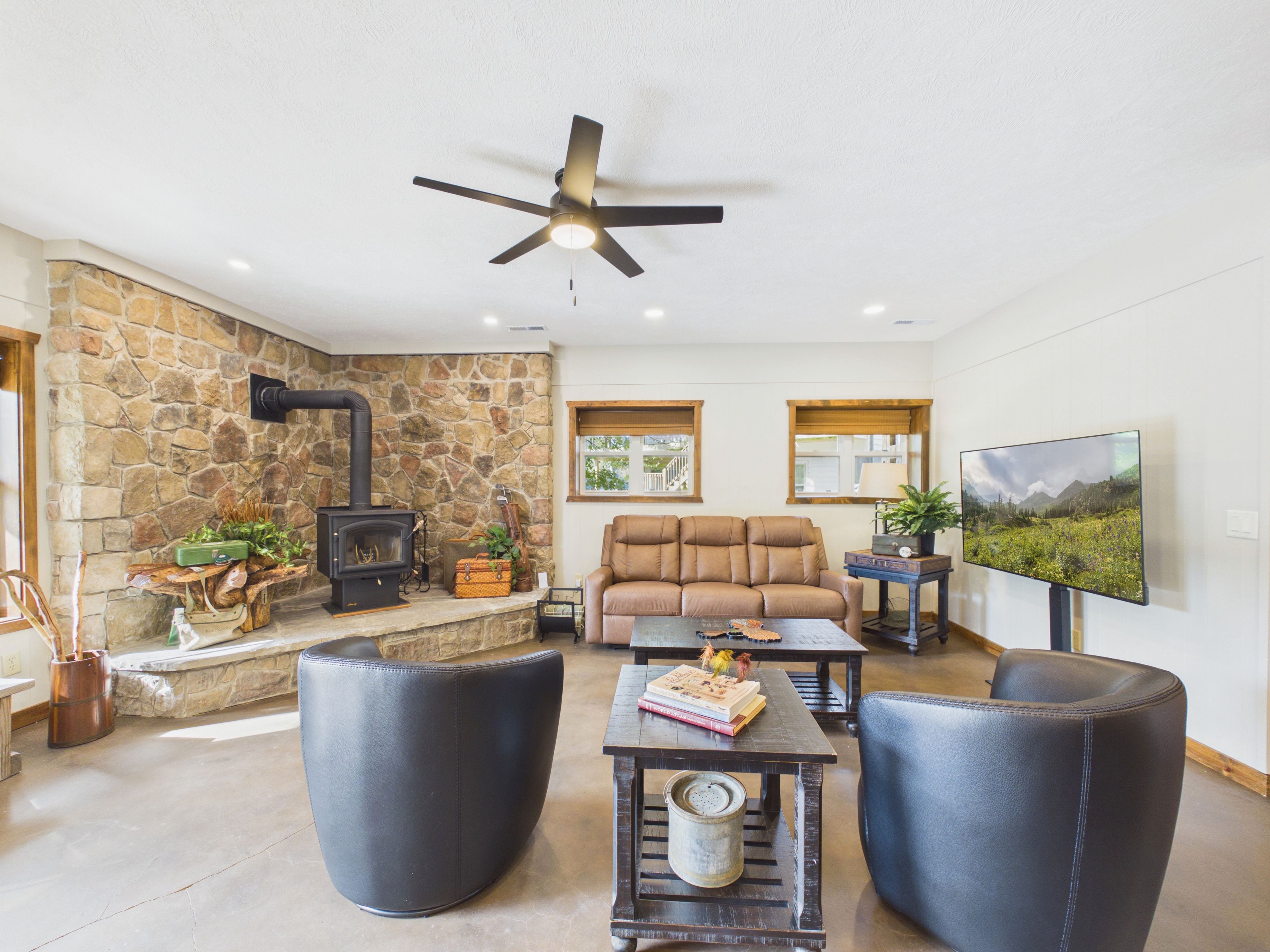 Una sala de estar con pared de piedra, chimenea, sofá y televisión.