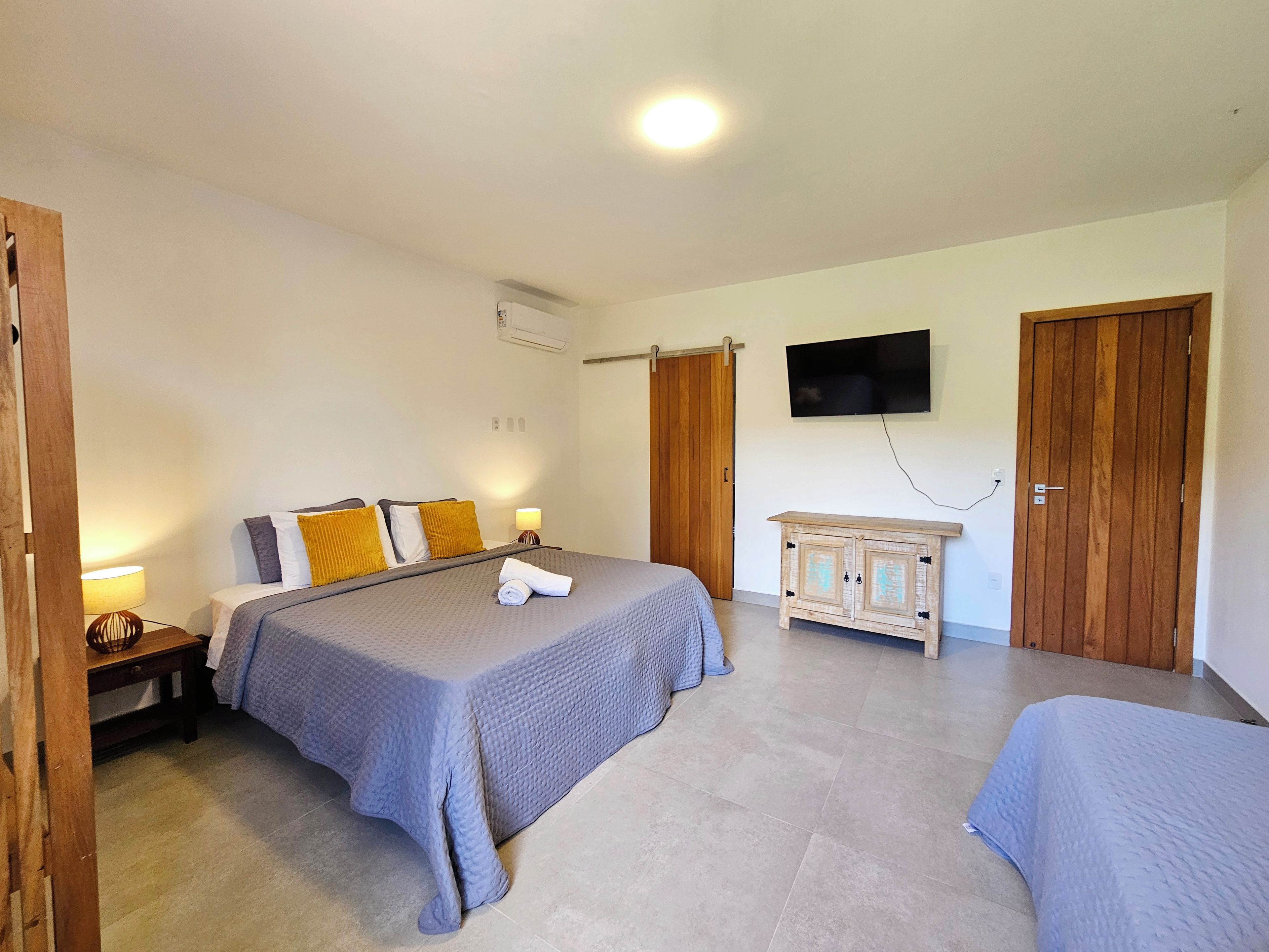 Een slaapkamer met een bed, nachtkastjes, een televisie en een kledingkast.
