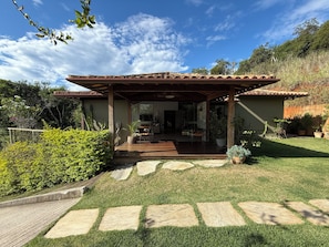 Ein Haus mit einer Terrasse, einer überdachten Sitzgelegenheit und einem Garten.