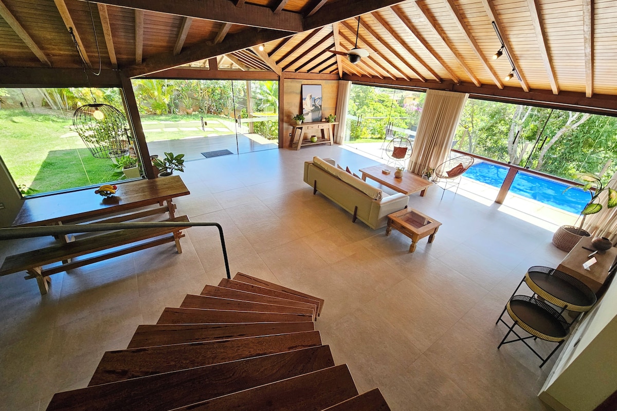 Ein geräumiger Wohnbereich mit Treppe, einer Couch, einem Couchtisch und Blick auf einen Swimmingpool.