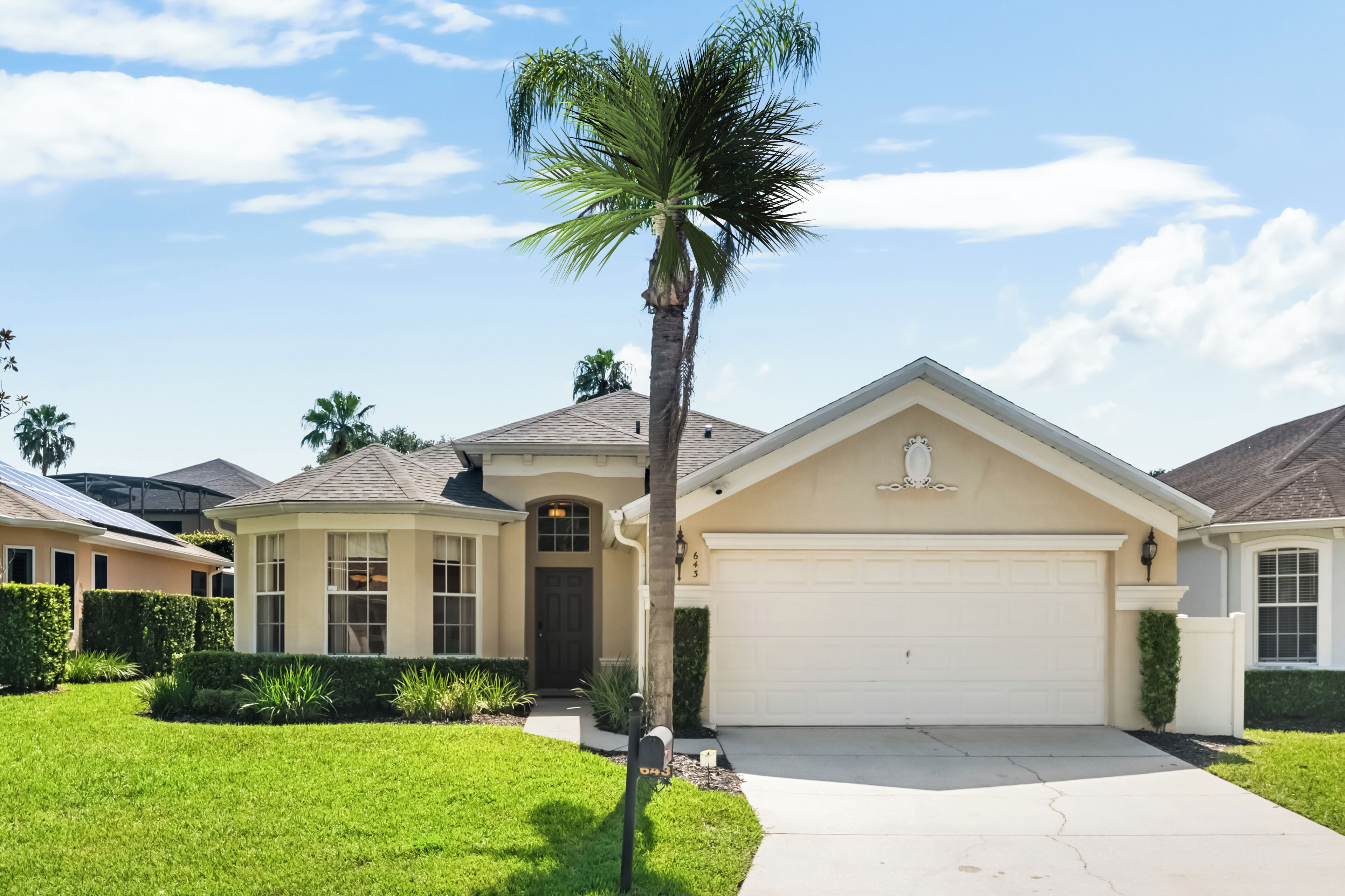 A residential house with a garage, a front yard, and a palm tree.