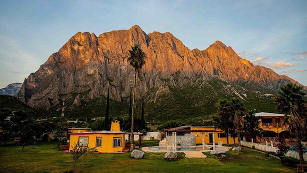 A mountainous landscape with a yellow building featuring a patio area.