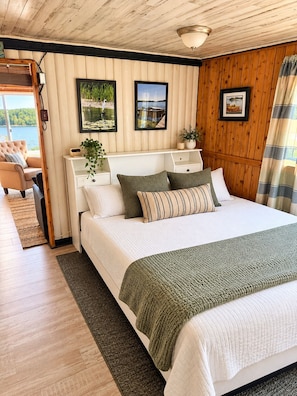 Une chambre à coucher avec un lit, une table de chevet, une lampe et une vue sur un lac.