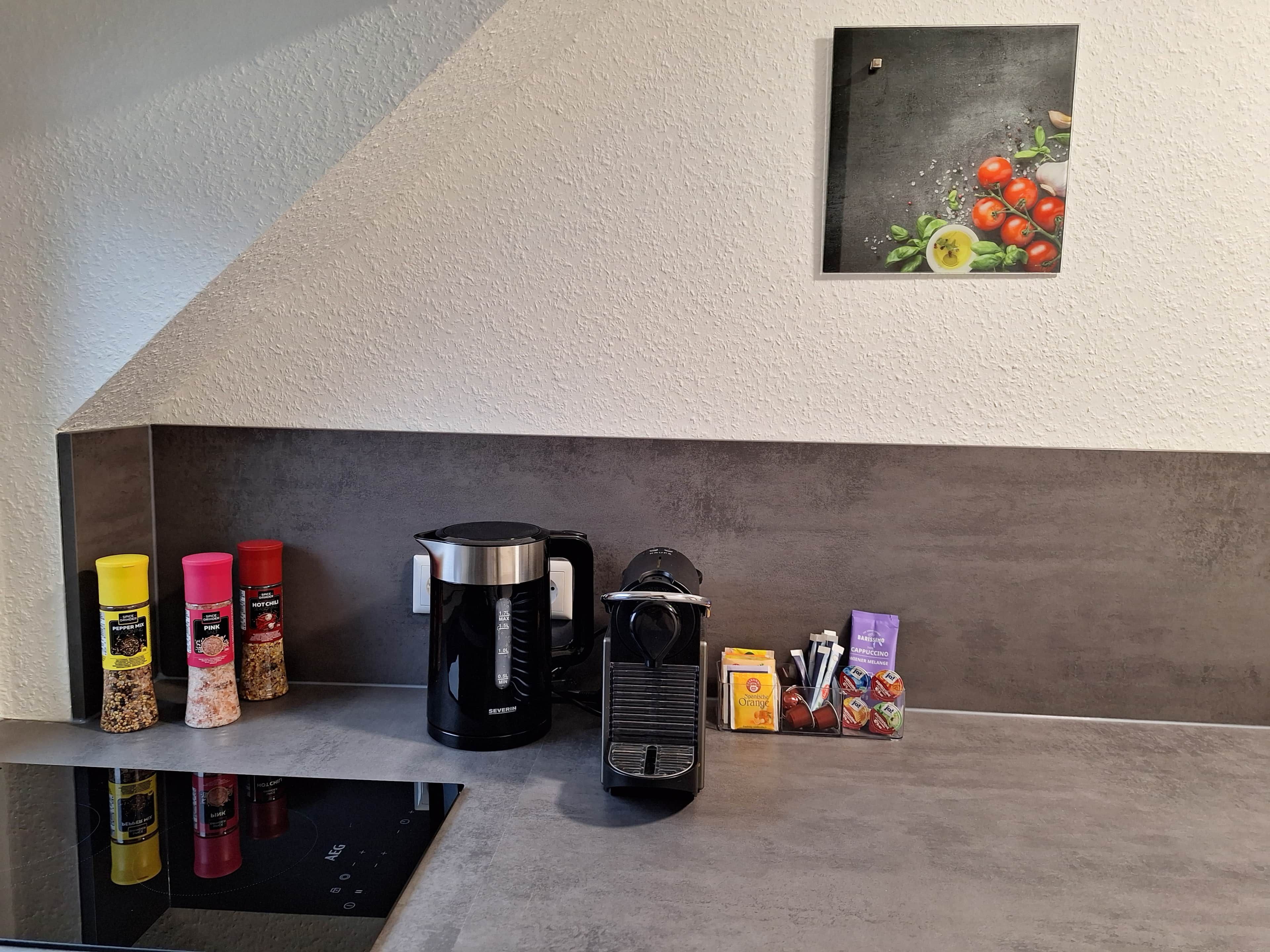 Una encimera de cocina con cafetera, especias y máquina de café.