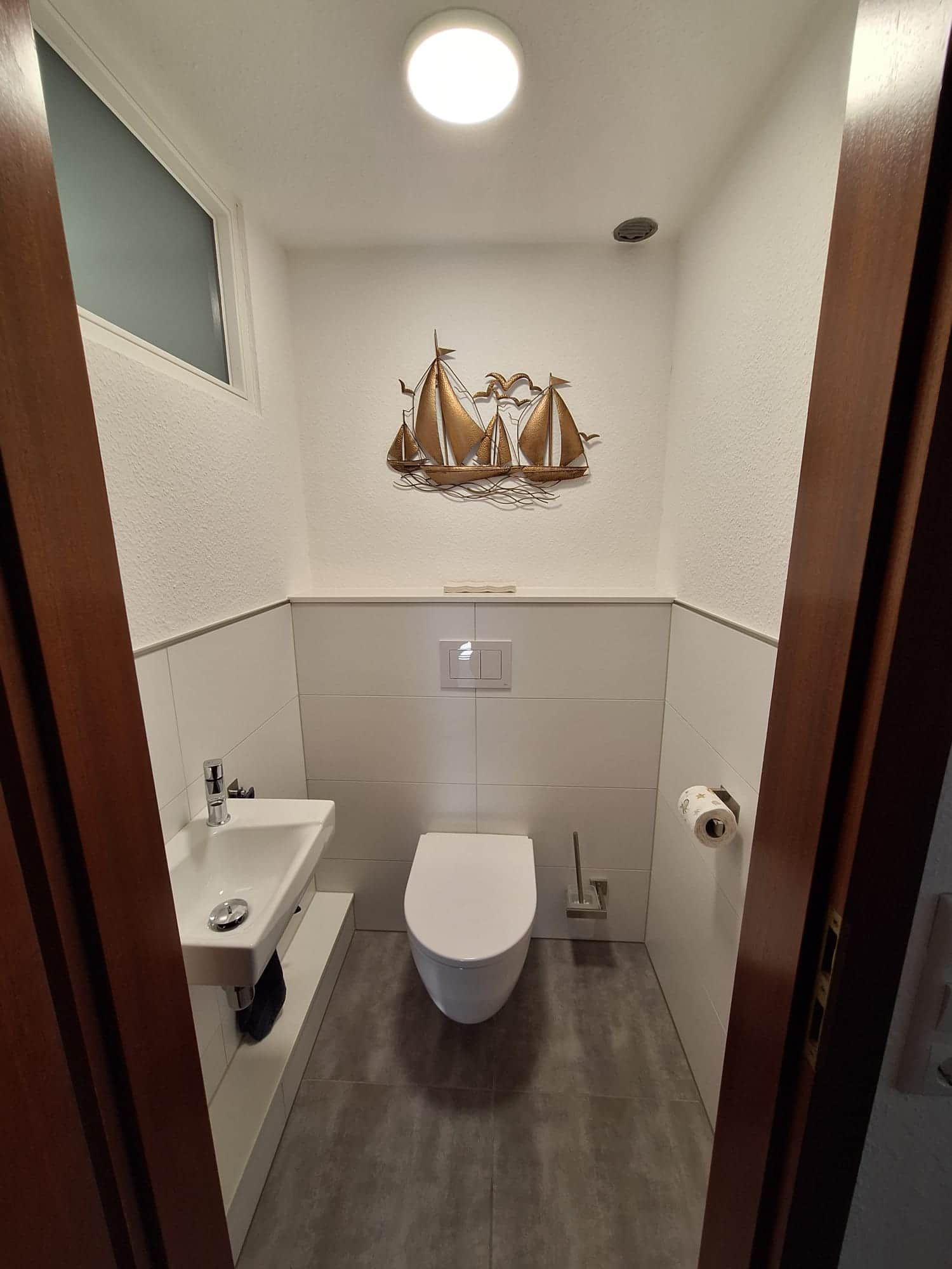 Ein kleines Badezimmer mit Toilette, Waschbecken und einer Dekoration über dem Waschbecken.
