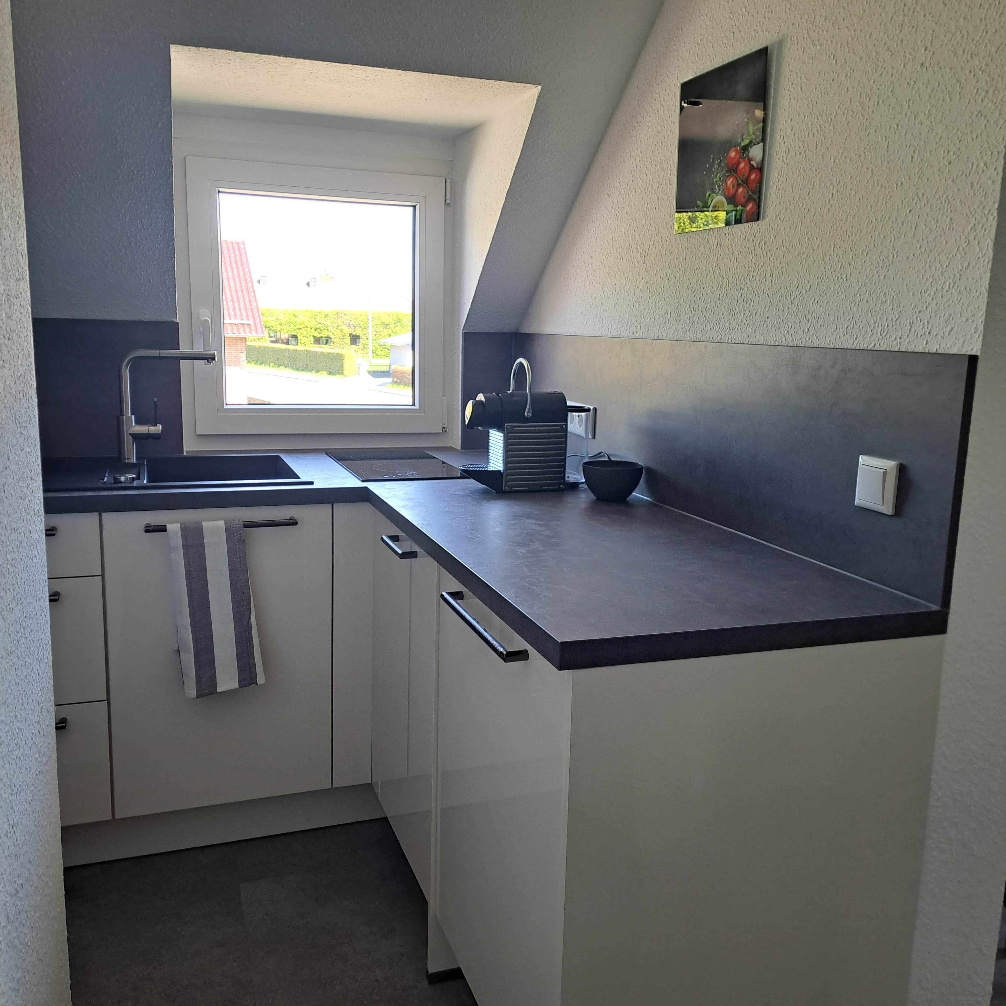Eine moderne Küche mit Fenster, Spüle, Wasserkocher und Schüssel.