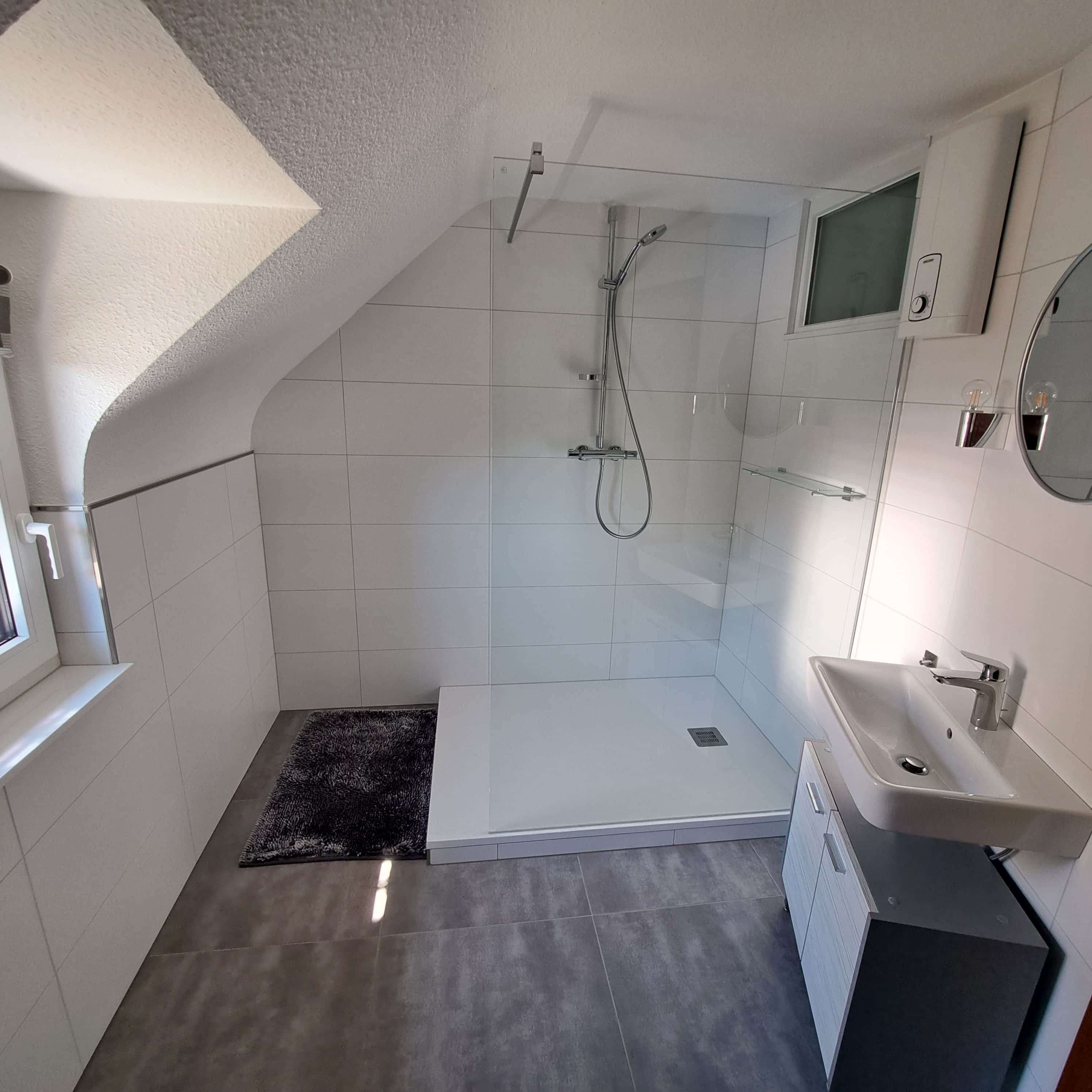 A modern bathroom with a shower, a sink, and a window.