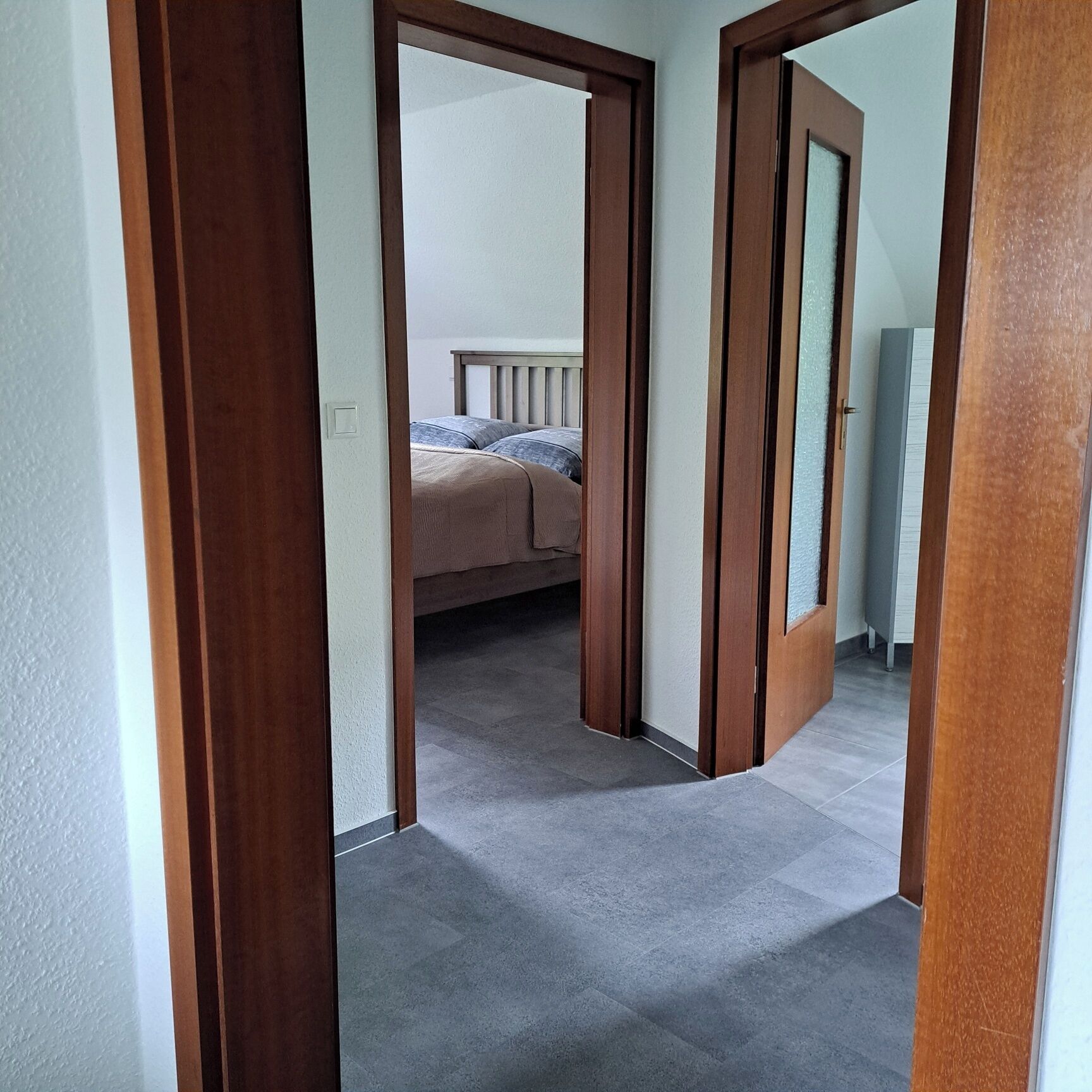 Un pasillo que conduce a un dormitorio con una cama y una mesita de noche.