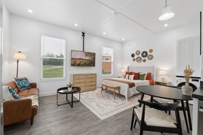 A modern living room with a sofa, a dining table, and a bed. - Modern Boxabl Casita | Stillwater OK | Pasadera 9 (Stillwater)