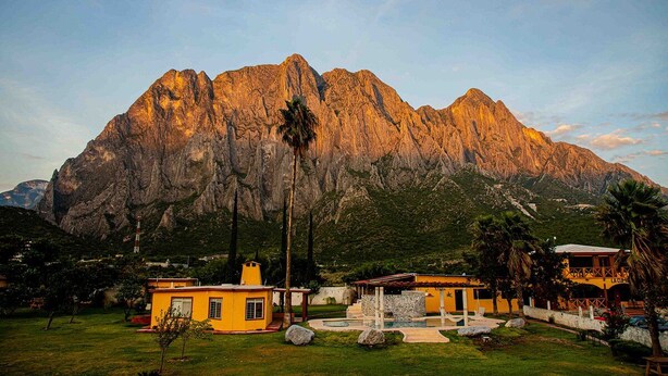 A mountain landscape with a yellow building in the foreground.