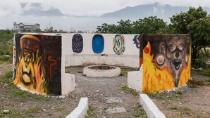 A concrete structure with colorful graffiti art, a circular opening, and a mountainous backdrop.