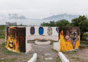 A concrete structure with colorful graffiti art, a circular opening, and a mountainous backdrop.