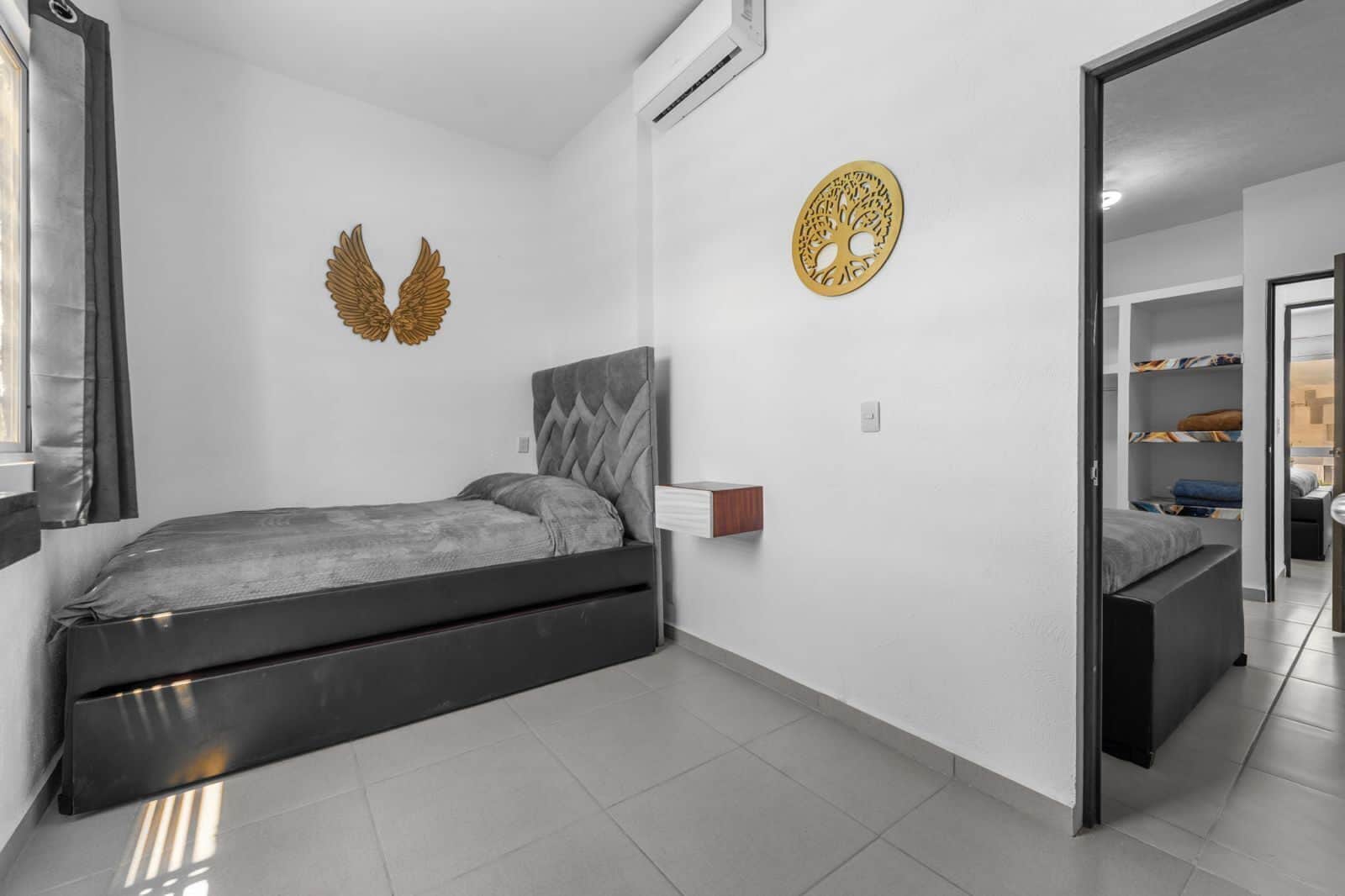 Une chambre moderne avec un lit, un climatiseur fixé au mur et un élément décoratif mural.