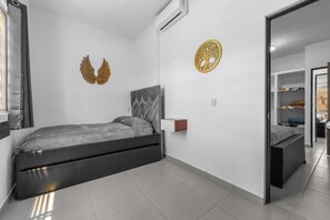 A modern bedroom with a bed, a wall-mounted air conditioner, and a decorative wall piece.