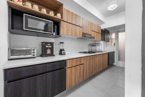 A modern kitchen with a microwave, toaster, blender, and gas stove.