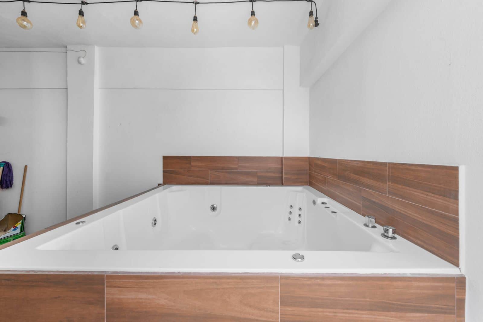 A modern bathroom with a freestanding bathtub, wooden wall paneling, and a ceiling light fixture.