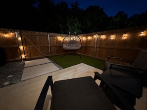 A backyard with a wooden fence, a hanging chair, and outdoor furniture. - Serene 2-bedroom townhome with AC in vibrant Dallas (Dallas)