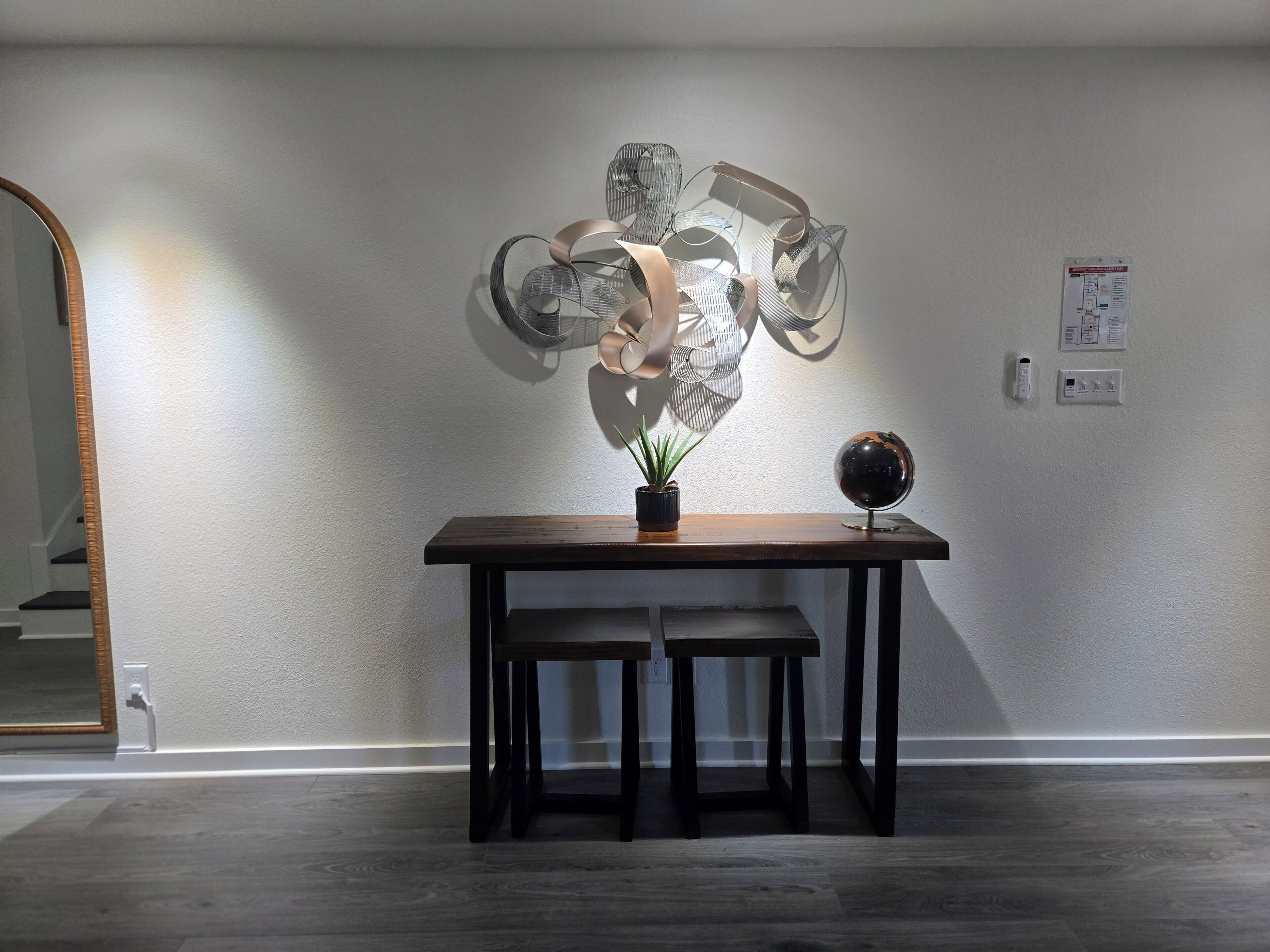 Une pièce comprenant une table en bois, un globe terrestre et une sculpture abstraite fixée au mur.