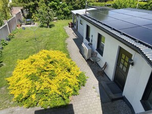 En bostadsfastighet med ett solpanelbeklätt tak, en stenlagd gång och en gulblommande buske.